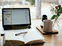 an open notebook next to a laptop with a blog open